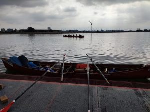 Ruderboot am Steg mit weiteren Ruderboot im Hintergrund auf dem Wasser