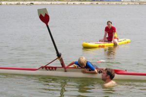 Kind zieht sich aus dem Wasser in einen Rudereiner und hält dabei das Gleichgewicht